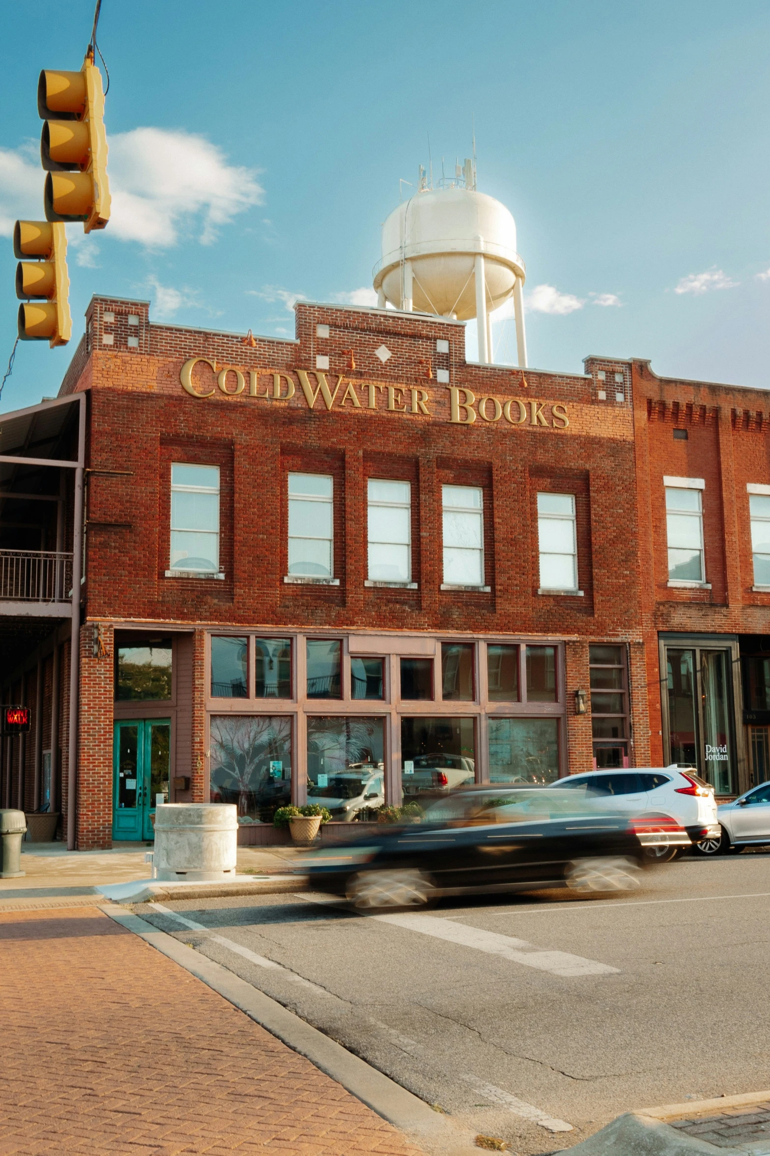 the street in front of a large brick building with a red traffic light on it