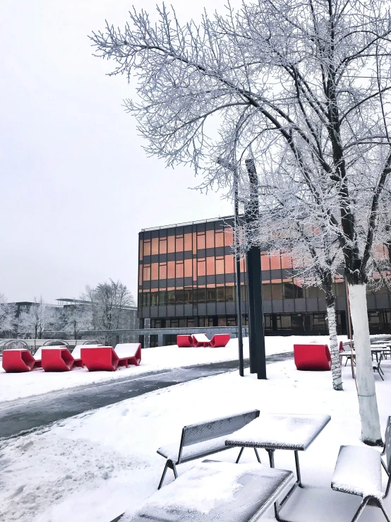 a public park in winter with benches and tables covered in snow