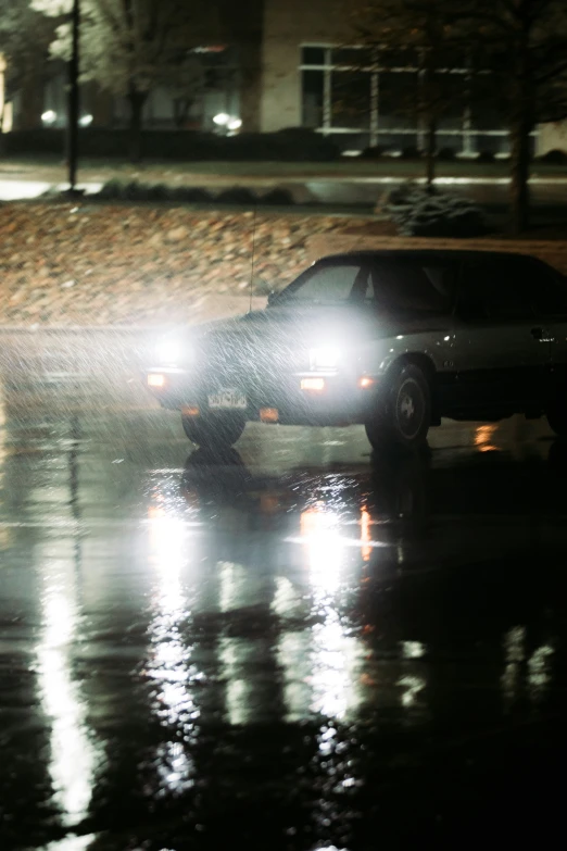 two cars driving down a rainy street under umbrellas