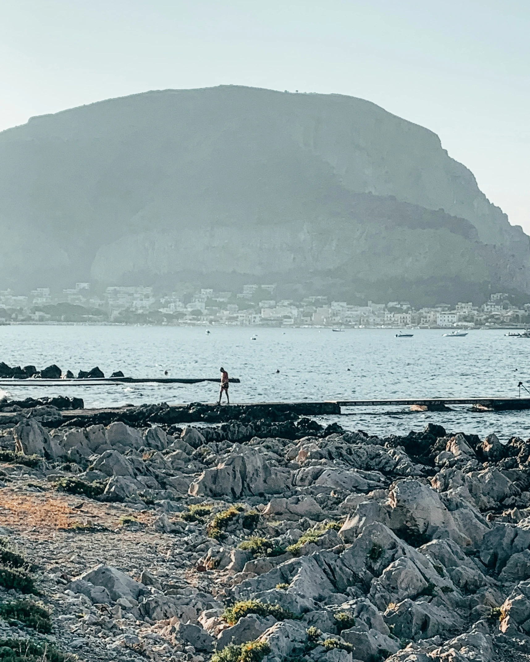 an person walks along the shoreline on a clear day