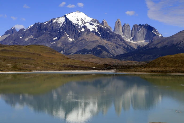 snow covered mountains and a blue sky with calm water