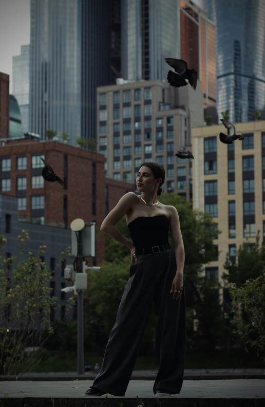 a girl stands outside and looks at birds flying above her