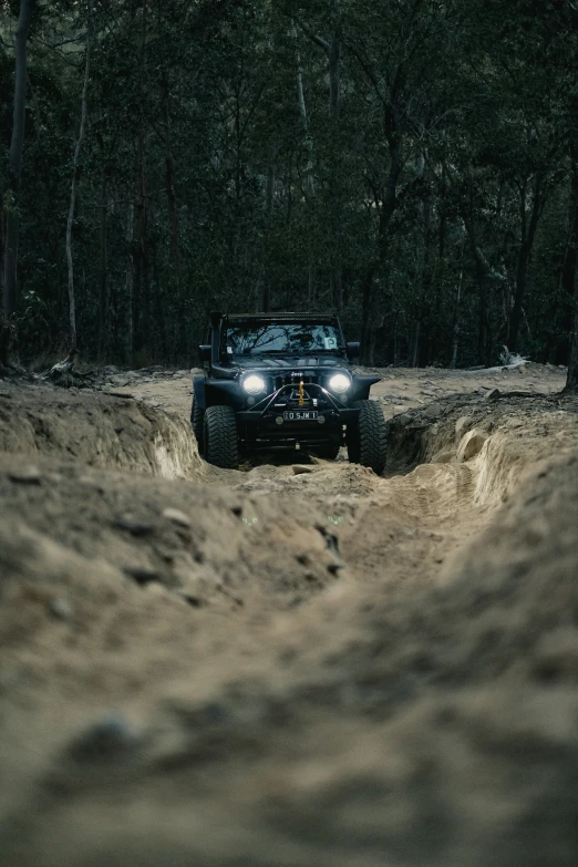 a jeep driving through the dirt in the woods