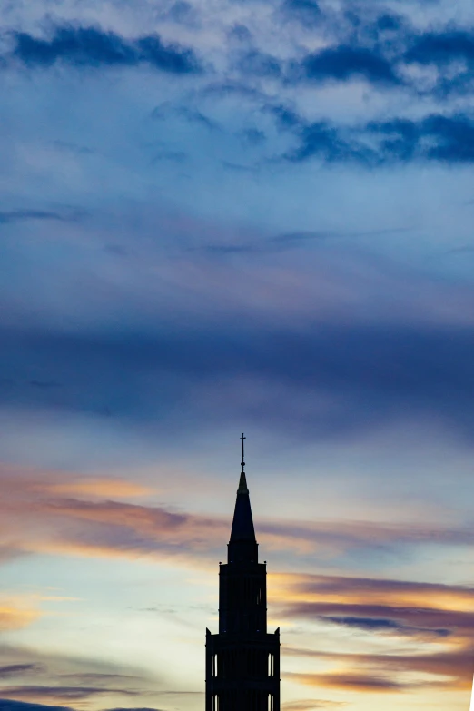 a big tower with a steeple at dusk