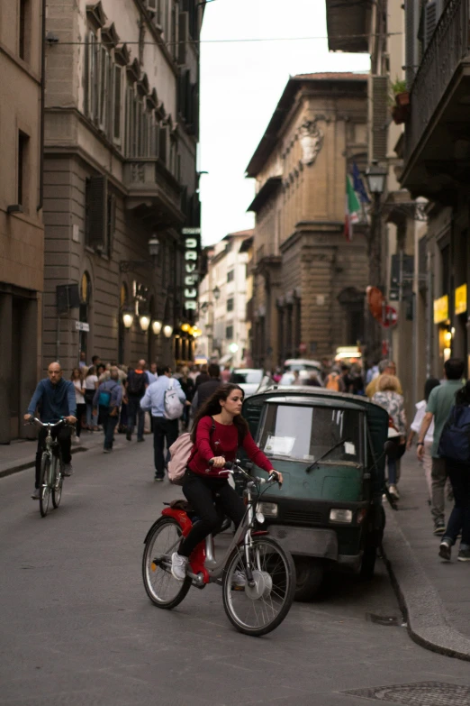 a woman riding on the back of a bike through an alleyway