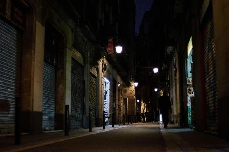 a man is walking down a street with the dark surrounding him