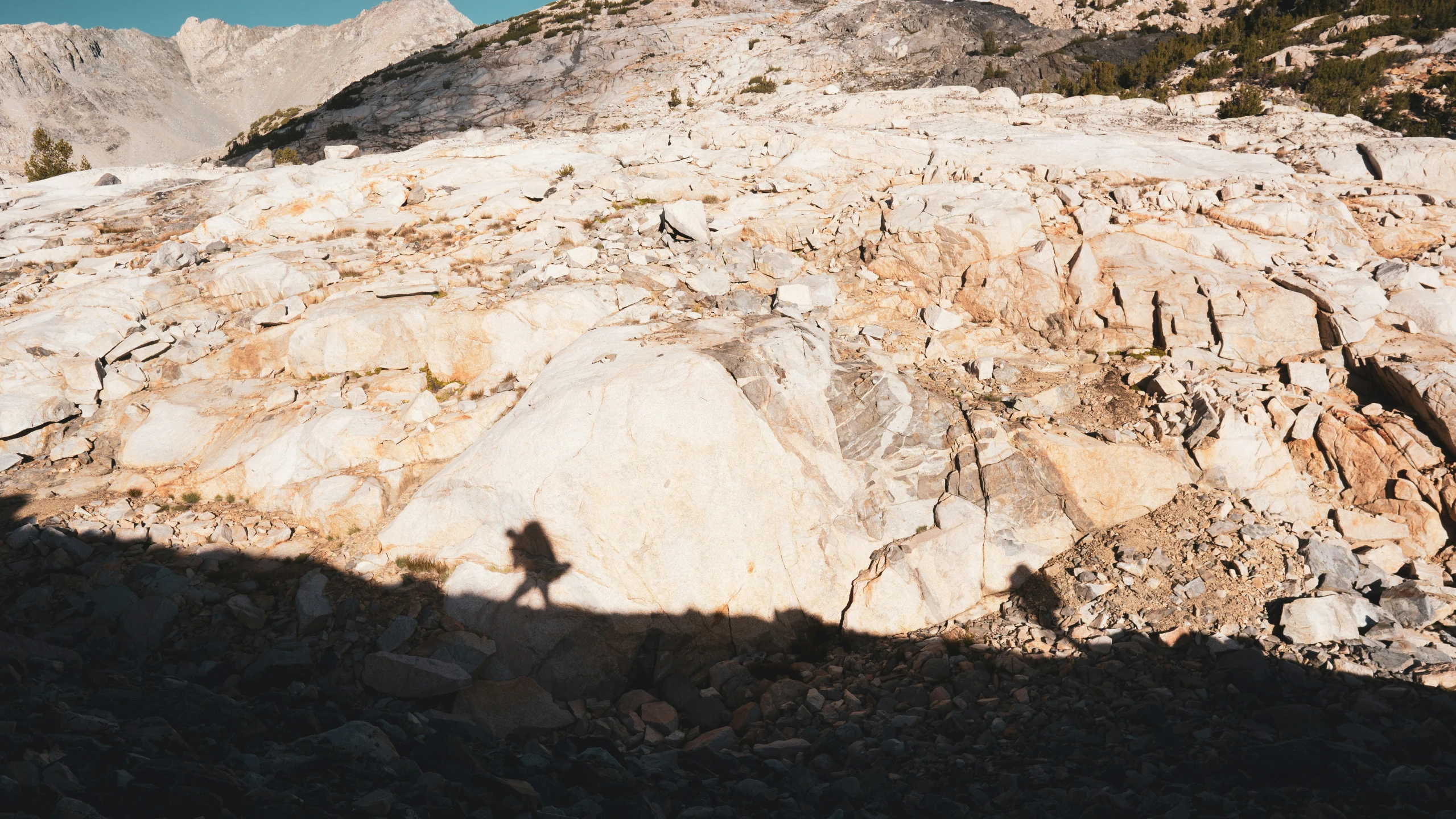 a shadow shows a hiker standing on a rock