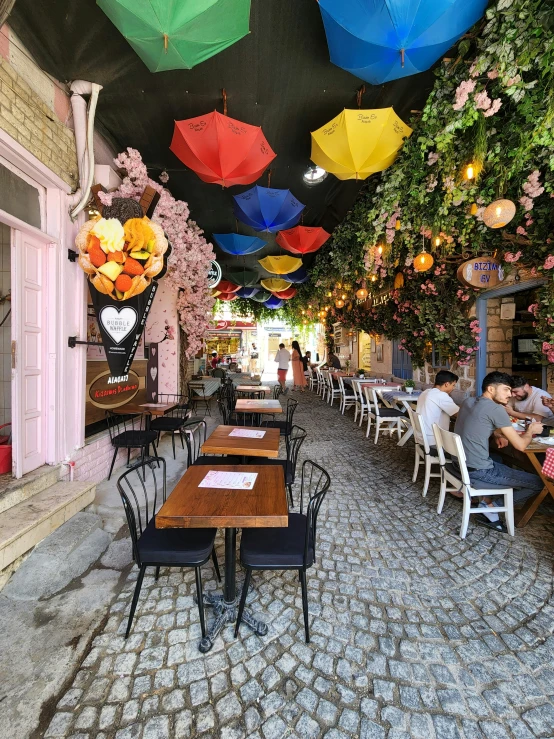 there are lots of umbrellas hanging over tables in this restaurant