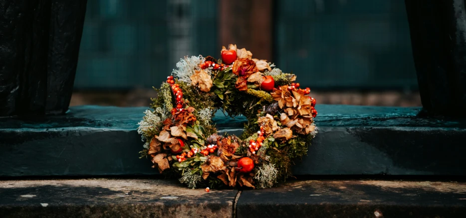 an evergreen wreath with berries sits on the steps