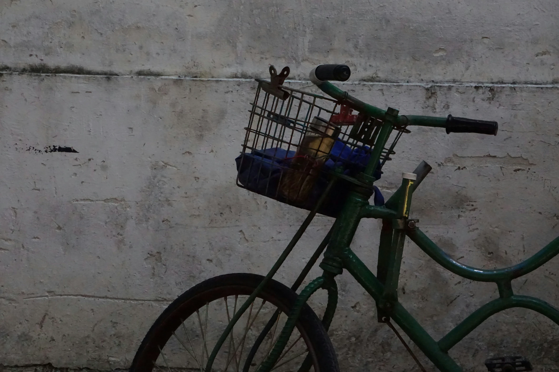 a bicycle leaning against a stone wall with a basket on the front