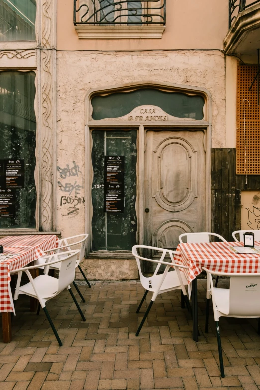 two tables with checkeredcloths are placed next to a building