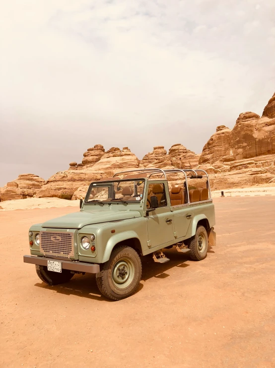 a dusty sandy road in the desert with a blue truck and tan car