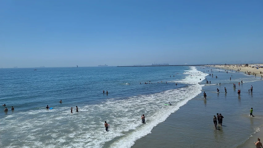 people walk into the ocean from the beach