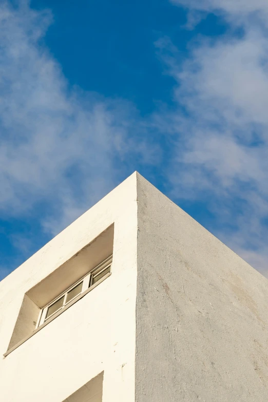 a white tower with a window and clouds in the background