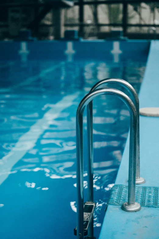 a pool with a blue diving board and a railing