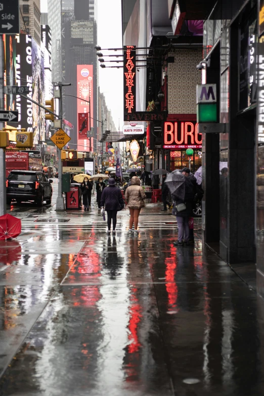 the people walk down the sidewalk on the rainy day