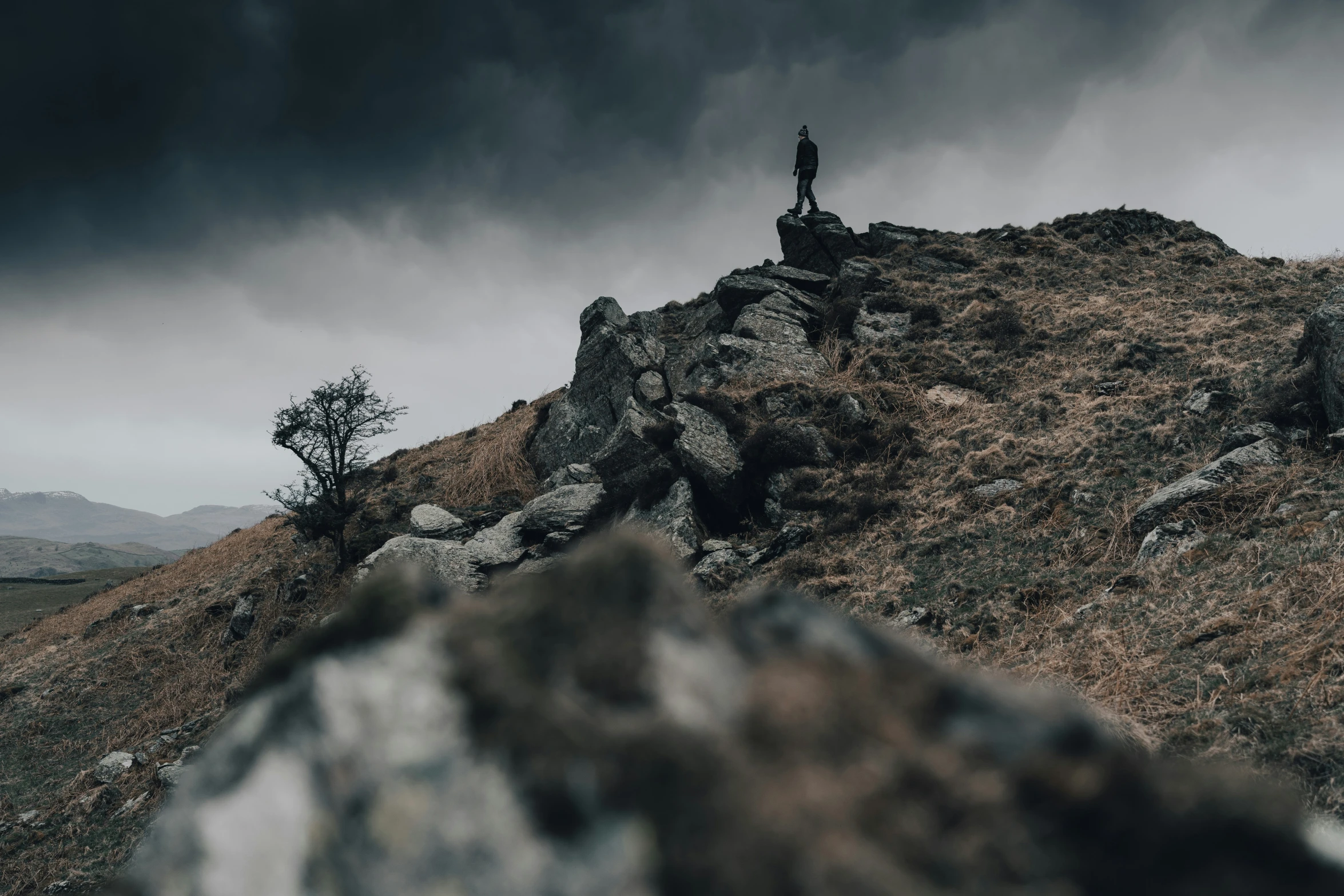 person standing on a mountaintop with a black cloud in the background