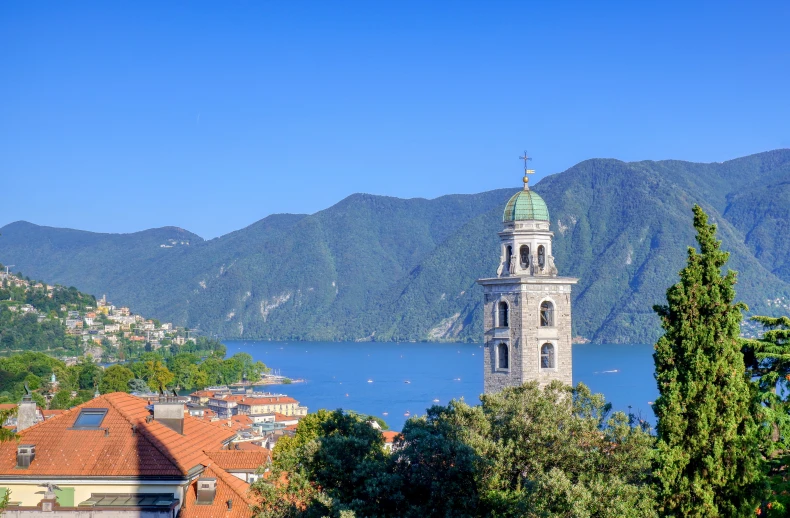 the tower of a church sits next to the water