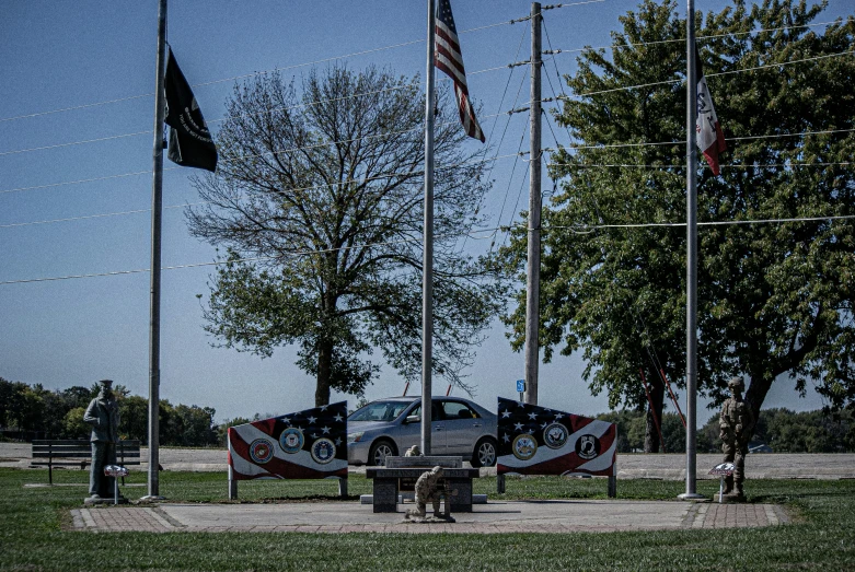 some cars on a road next to two flags and trees