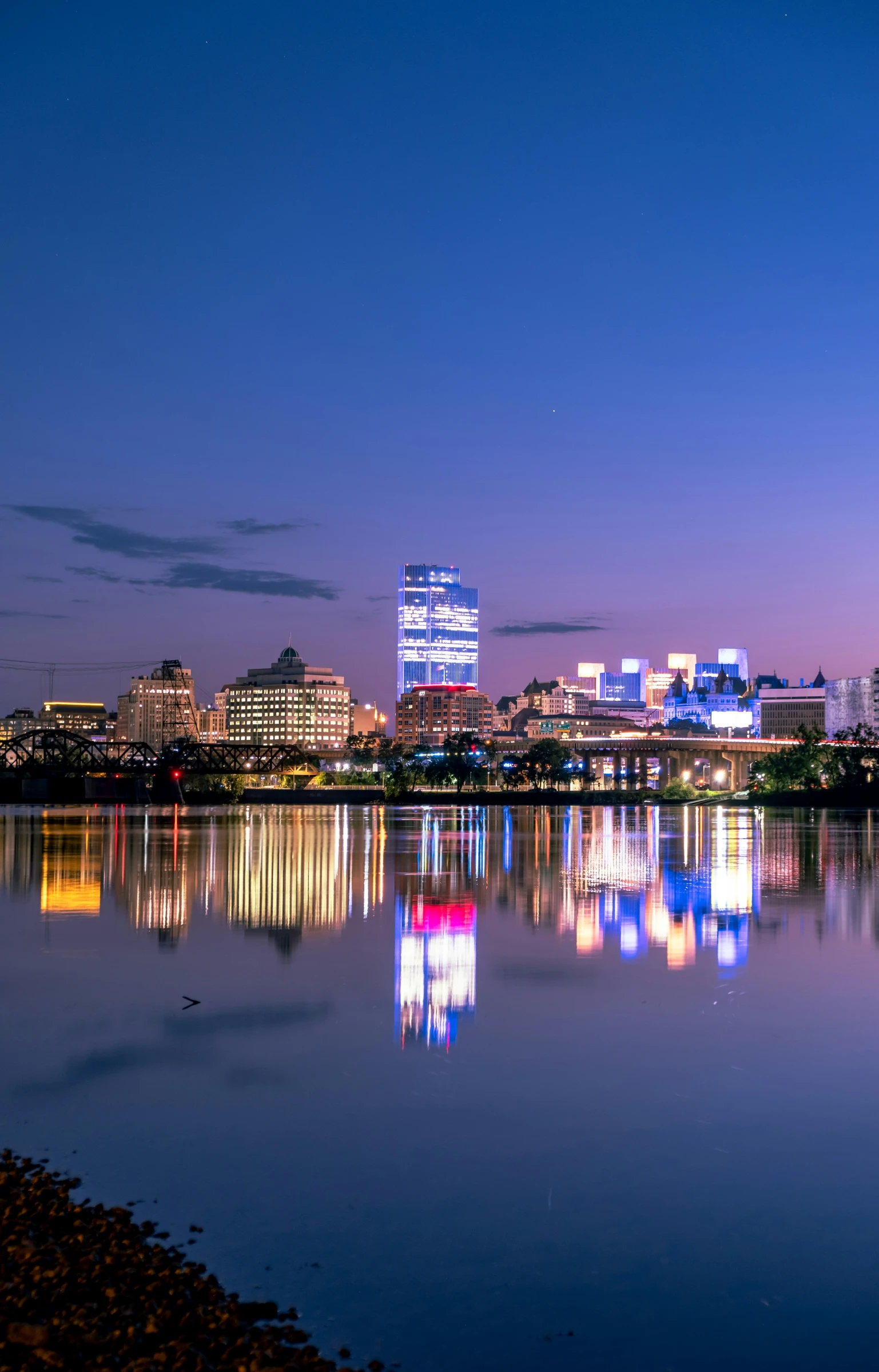 a city skyline and the reflection in the water at dusk