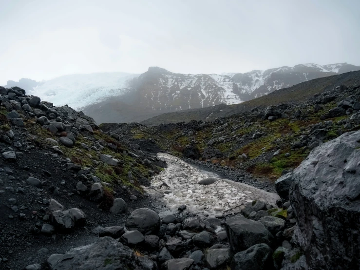 a rock and grass field is on the edge of a mountain range