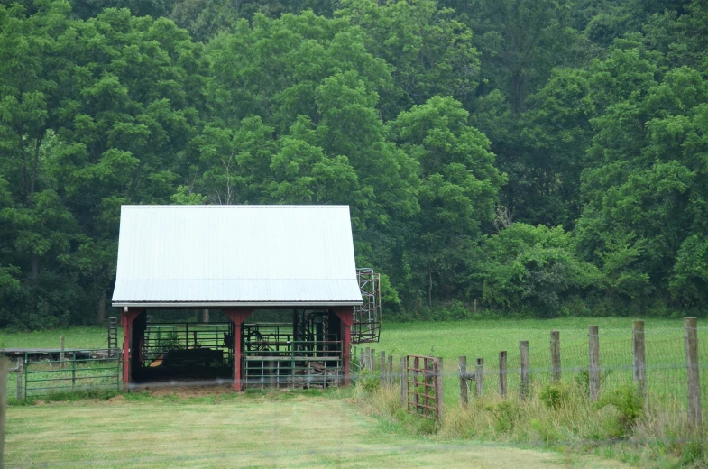 an empty barn in the middle of a green pasture