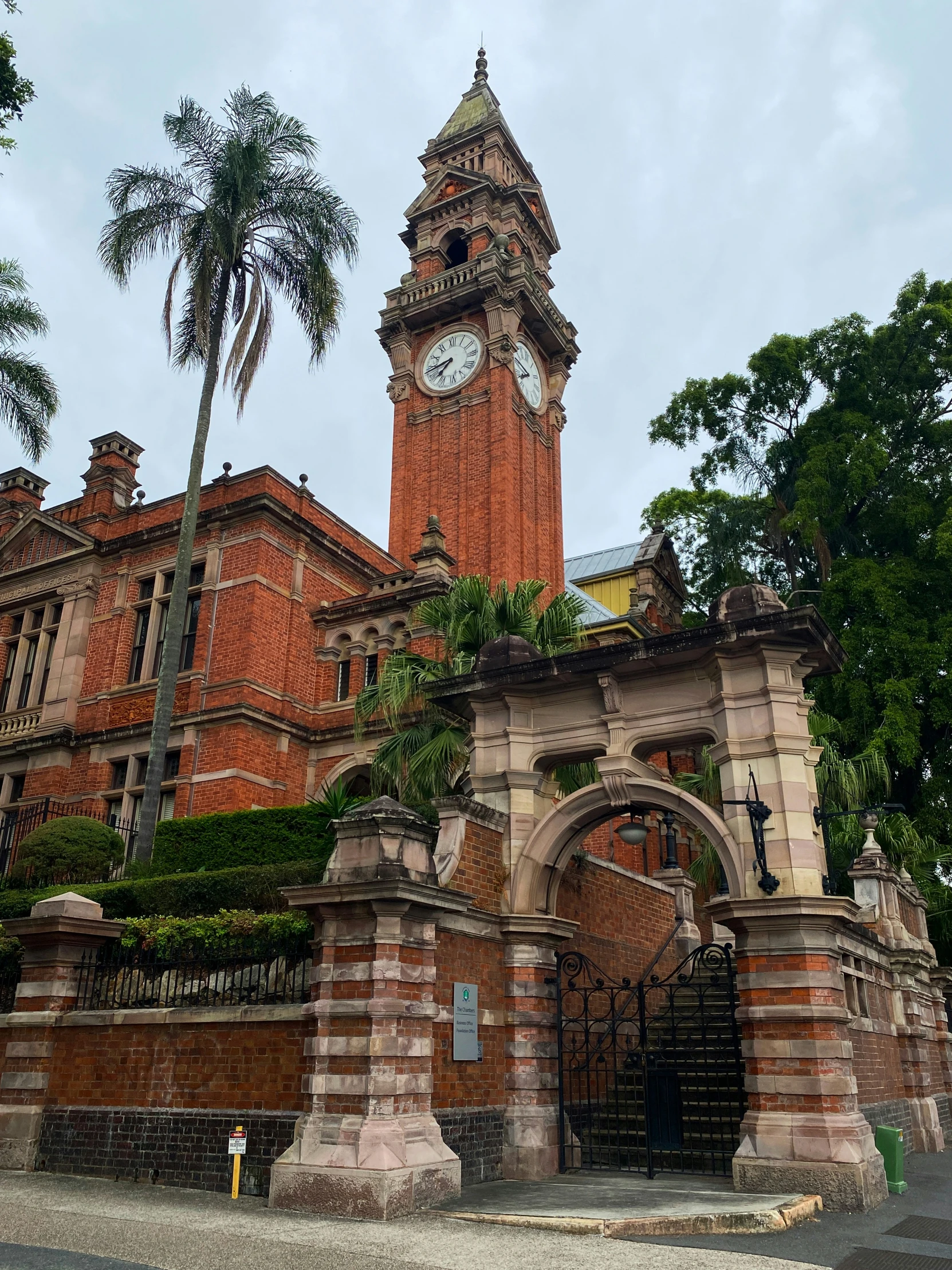 the clock tower stands high above a brick structure