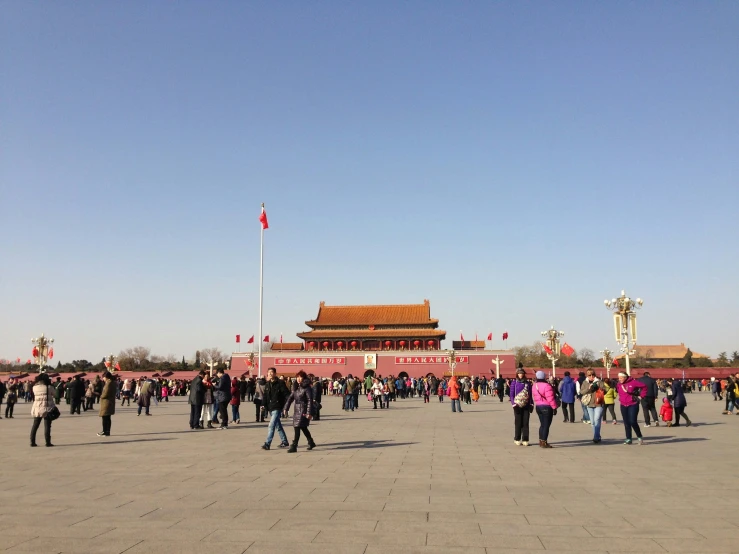 a large crowd walking towards a building on a sunny day