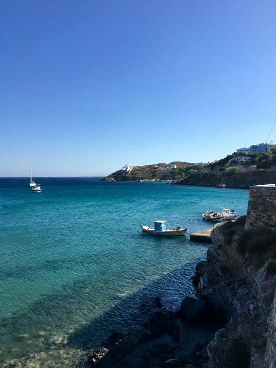 several boats on clear water near a rocky shoreline