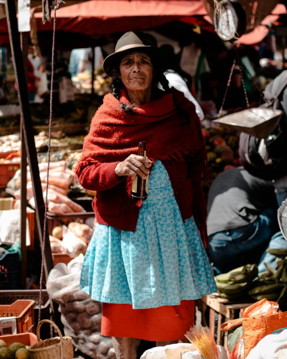 an old woman with a red coat in the middle of a market