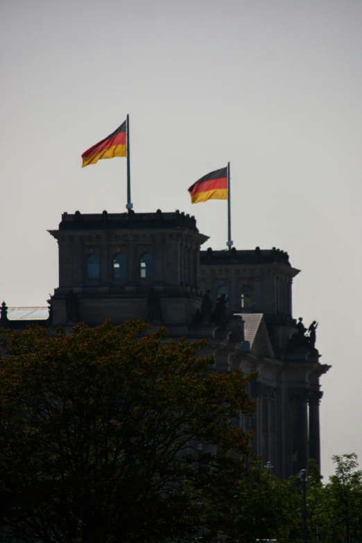 the flags are high up in the air over the buildings