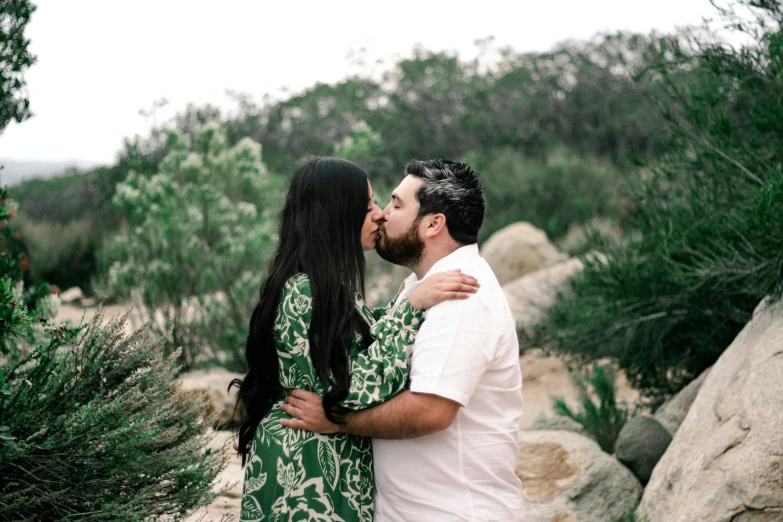 a young man and woman emcing under trees