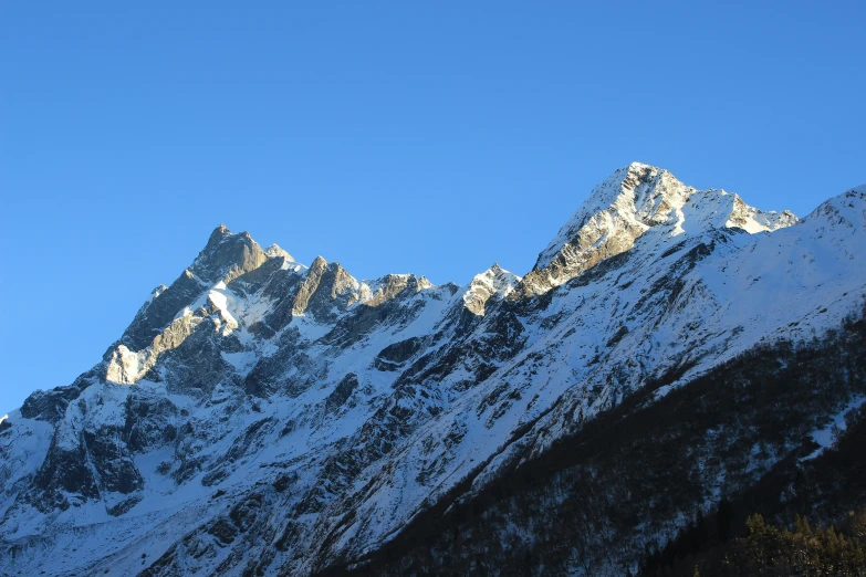 a bunch of mountains covered in snow against a blue sky