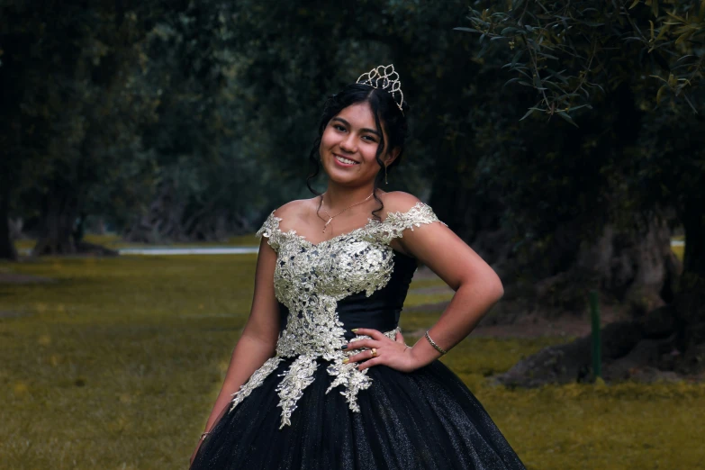 a girl in a black dress standing in front of some trees