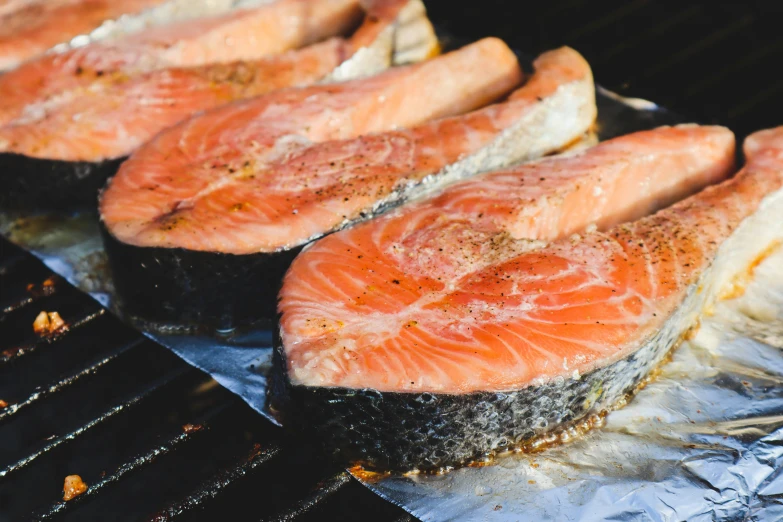 salmon steaks are cooking on a grill top