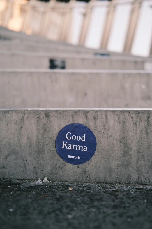 a blue plaque that says good karma and is mounted on a concrete wall