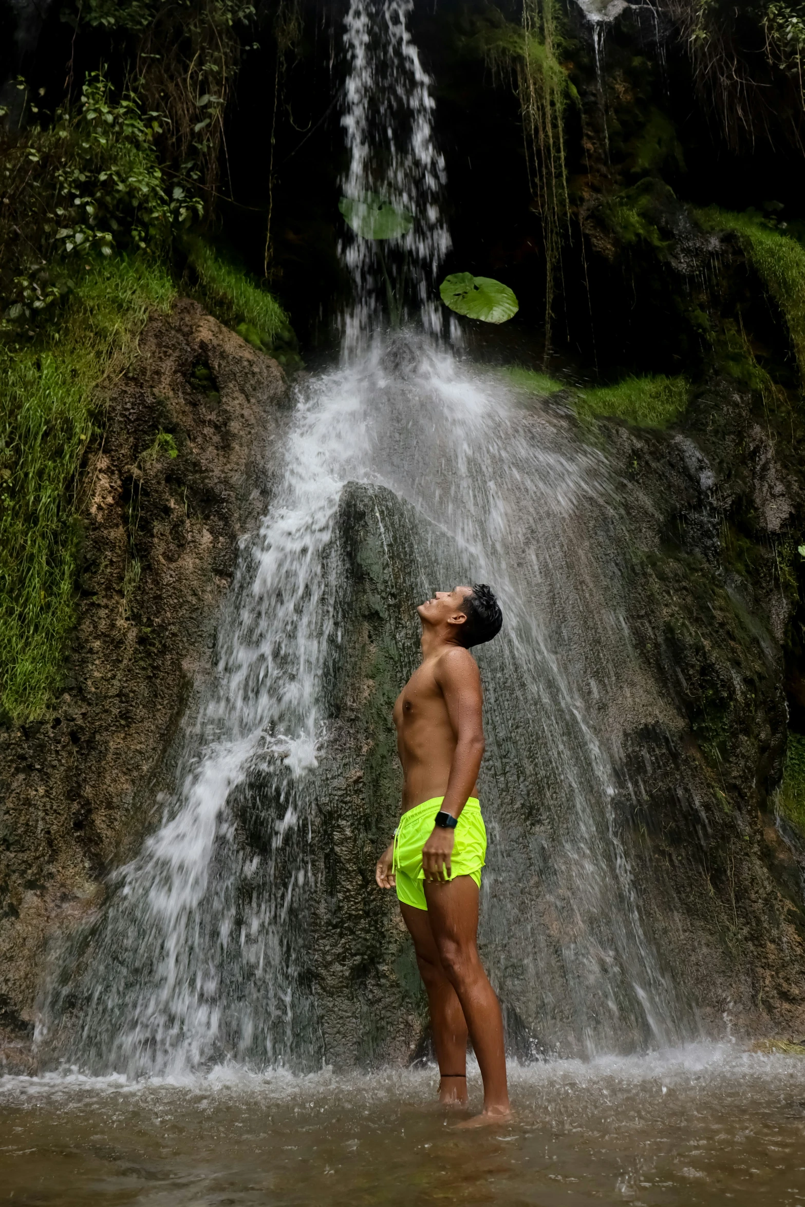 a man standing in the water next to a small waterfall