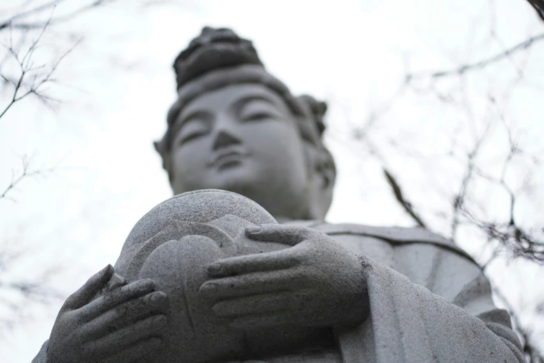 a statue holding an ornamental piece is pictured through the trees