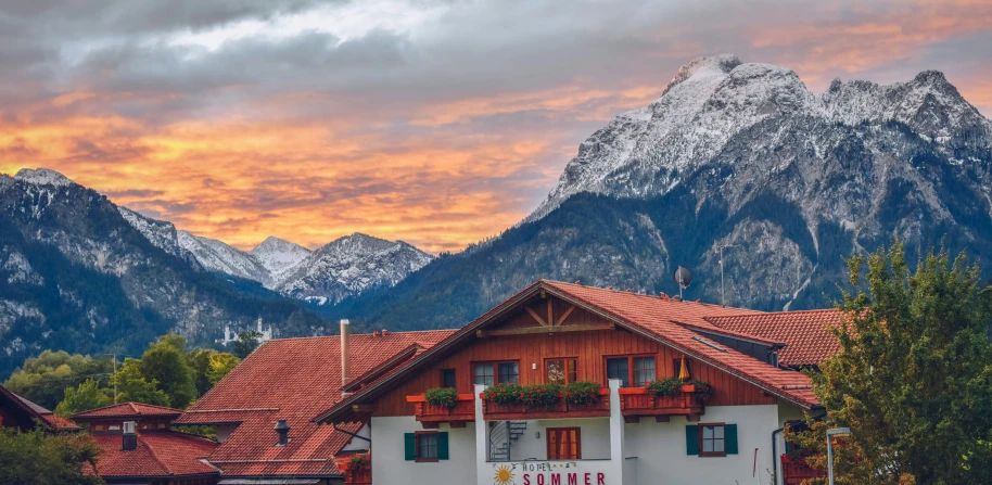 a mountain range covered in snow with some wooden buildings