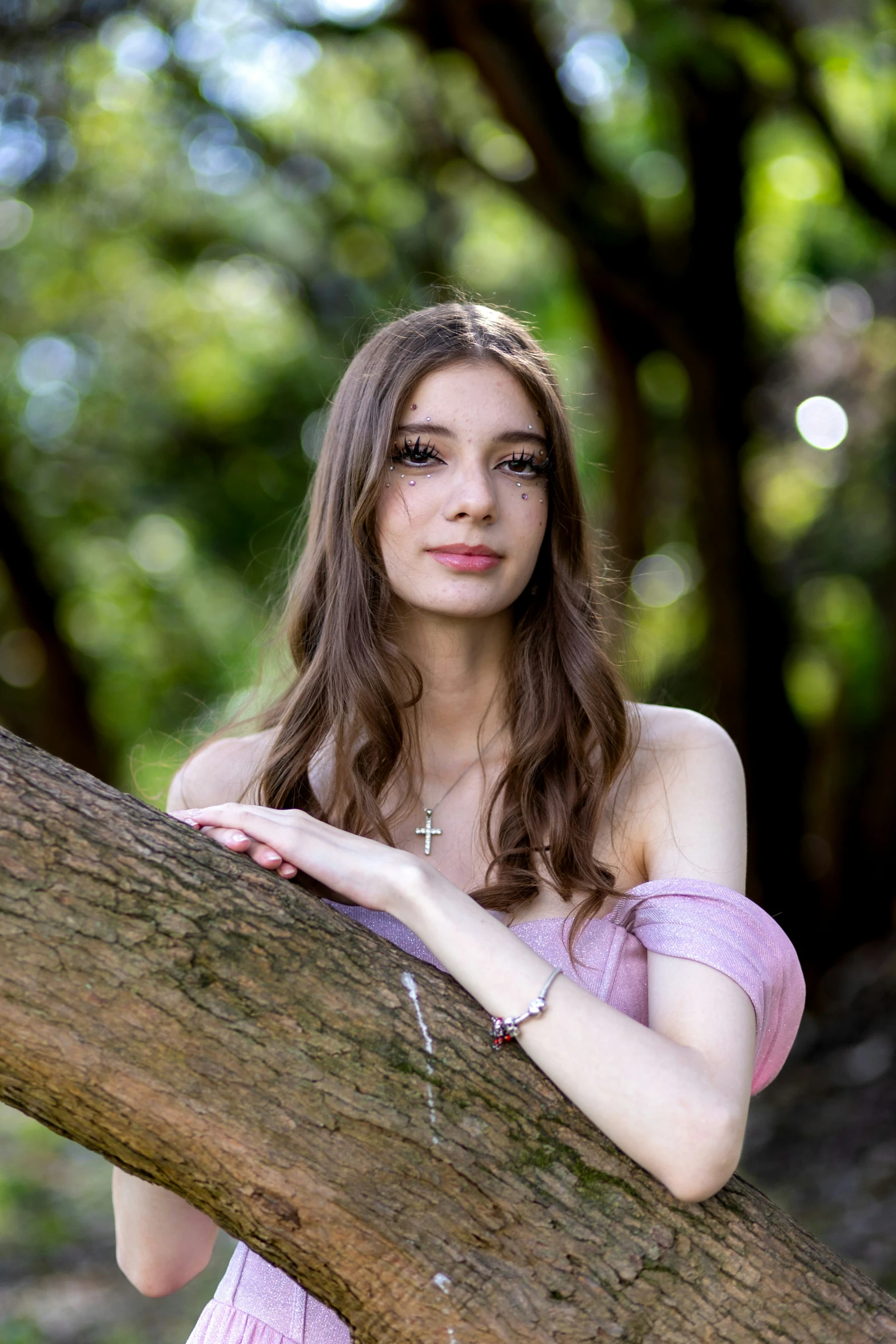 woman in pink shirt leaning up against a tree