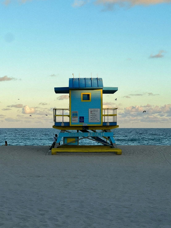a lifeguard chair in front of the water at sunset