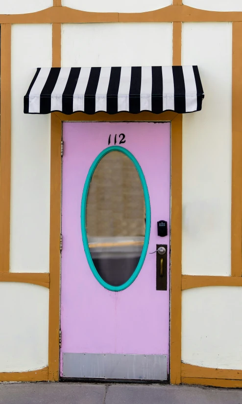 the door is brightly painted pink and yellow with a striped awning