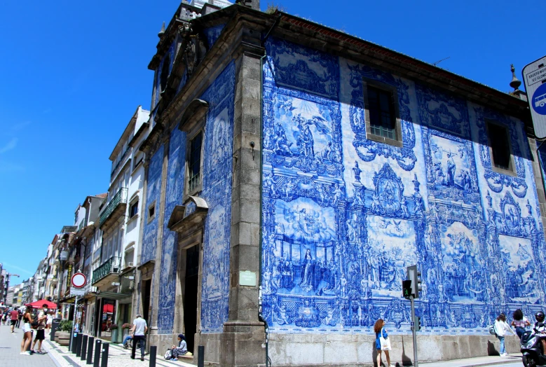 people standing on the sidewalk by a blue building