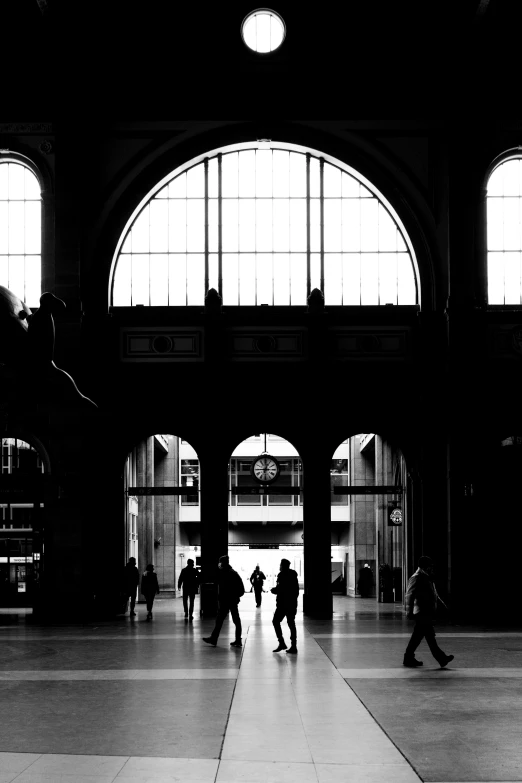 people walking in an underground train station with large windows