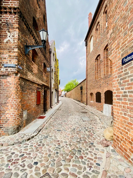an alley way that has cobblestone paved sides, and brick buildings