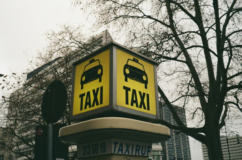 a yellow taxi tax sign on a pole with trees