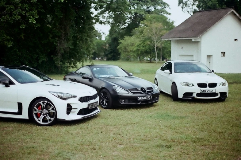 three cars parked side by side on a field next to trees