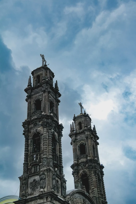 two tall towers next to each other under a blue cloudy sky