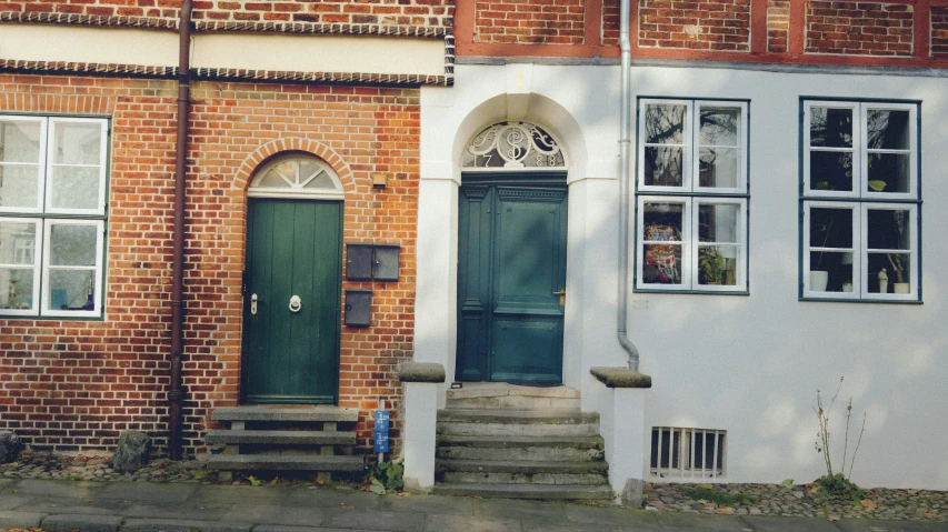 there is a green door and stairs in front of a brick house