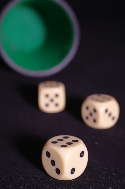 three dices sitting beside each other and a cup on the table